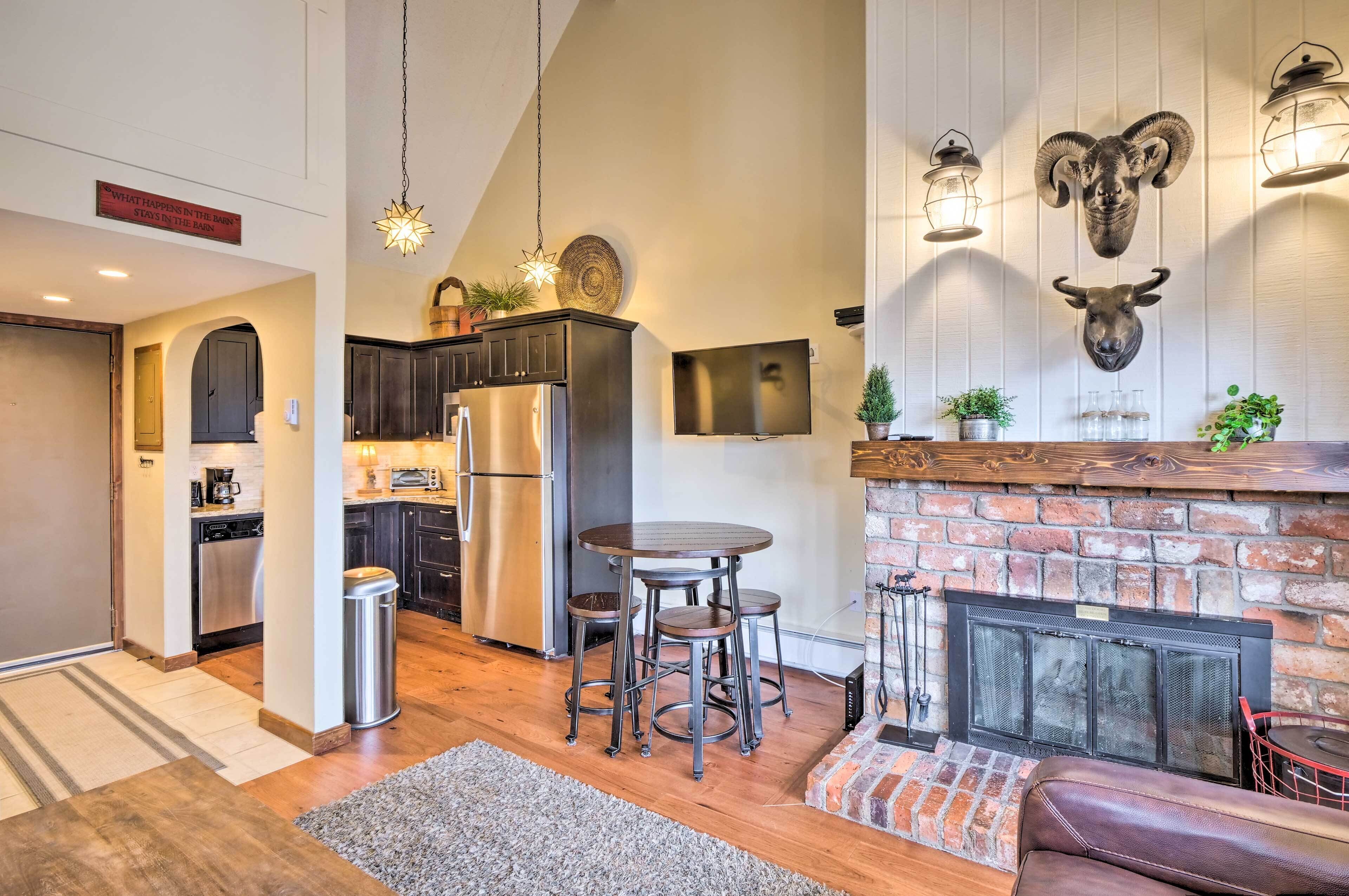 A modern kitchen with dark cabinetry, stainless steel appliances, and a dining area with stools.