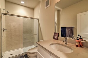 Un baño con cabina de ducha de vidrio, inodoro, lavabo y espejo.