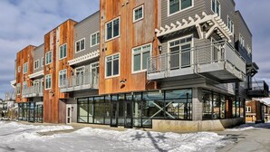 A multi-story building with a modern design, featuring large windows and a mix of wooden and metal materials.