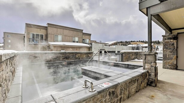 A hot tub area with stone walls and a view of modern buildings in the background.