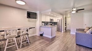 A modern kitchen with white cabinets, a microwave, and a refrigerator. There is a dining area with a table and chairs. - Cozy Studio w/ Balcony, Walk to Brian Head Resort! (Brian Head)