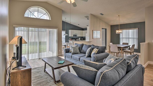A spacious living room with a gray sofa set, a wooden coffee table, and a ceiling fan. - 7 Mi to Wdw: Indian Ridge Home + Community Perks! (Kissimmee)