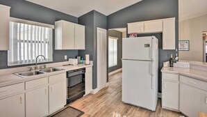 A modern kitchen with white cabinets, a double sink, and a built-in oven. - 7 Mi to Wdw: Indian Ridge Home + Community Perks! (Kissimmee)