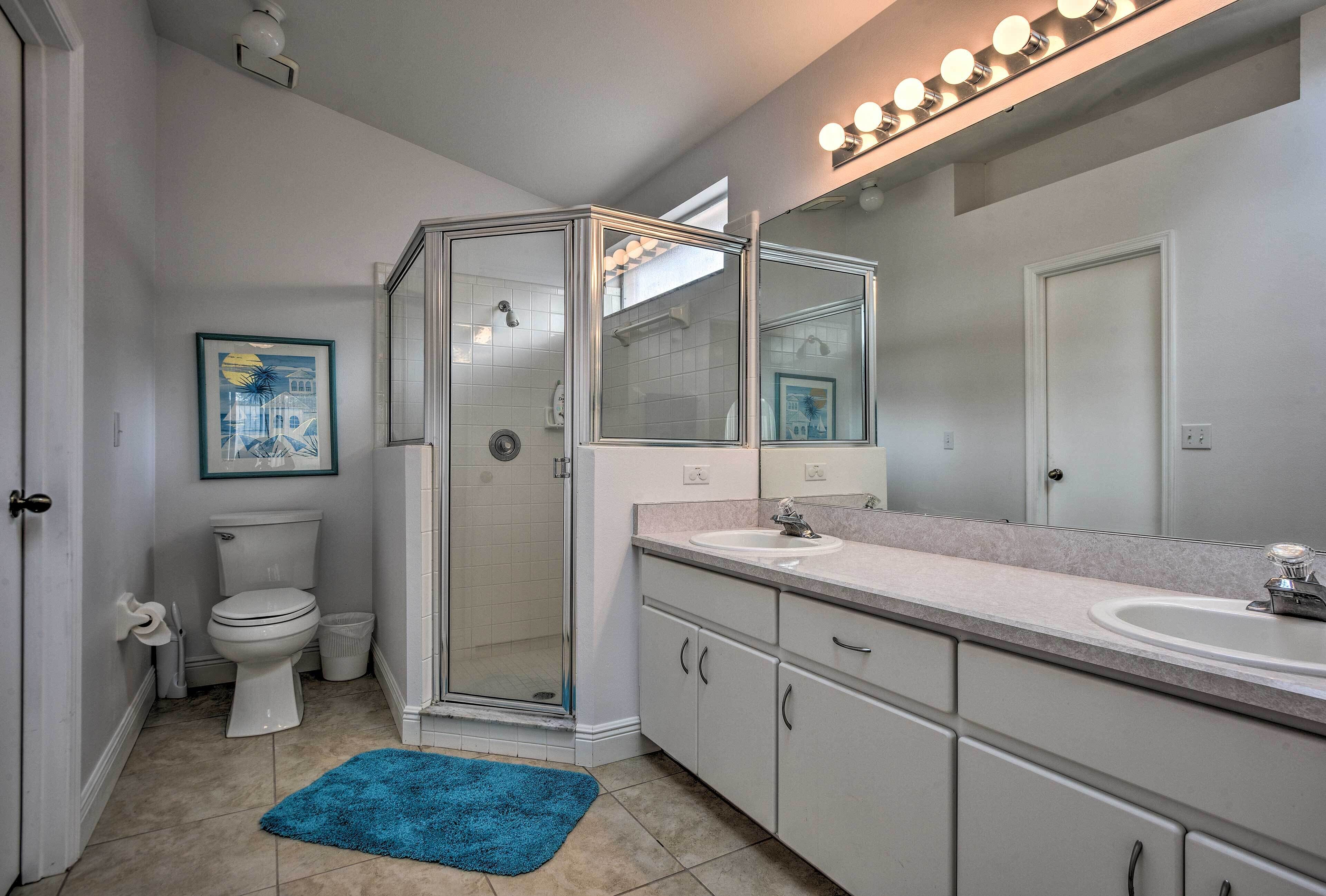 A modern bathroom with a glass-enclosed shower, a white toilet, a sink, and a large mirror.