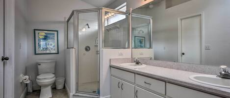 A modern bathroom with a glass-enclosed shower, a white toilet, a sink, and a large mirror.
