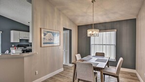 A dining area with a wooden table and chairs, a chandelier, and a window with blinds. - 7 Mi to Wdw: Indian Ridge Home + Community Perks! (Kissimmee)