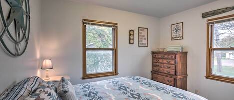 A bedroom with a bed, a dresser, a lamp, and a wall clock.