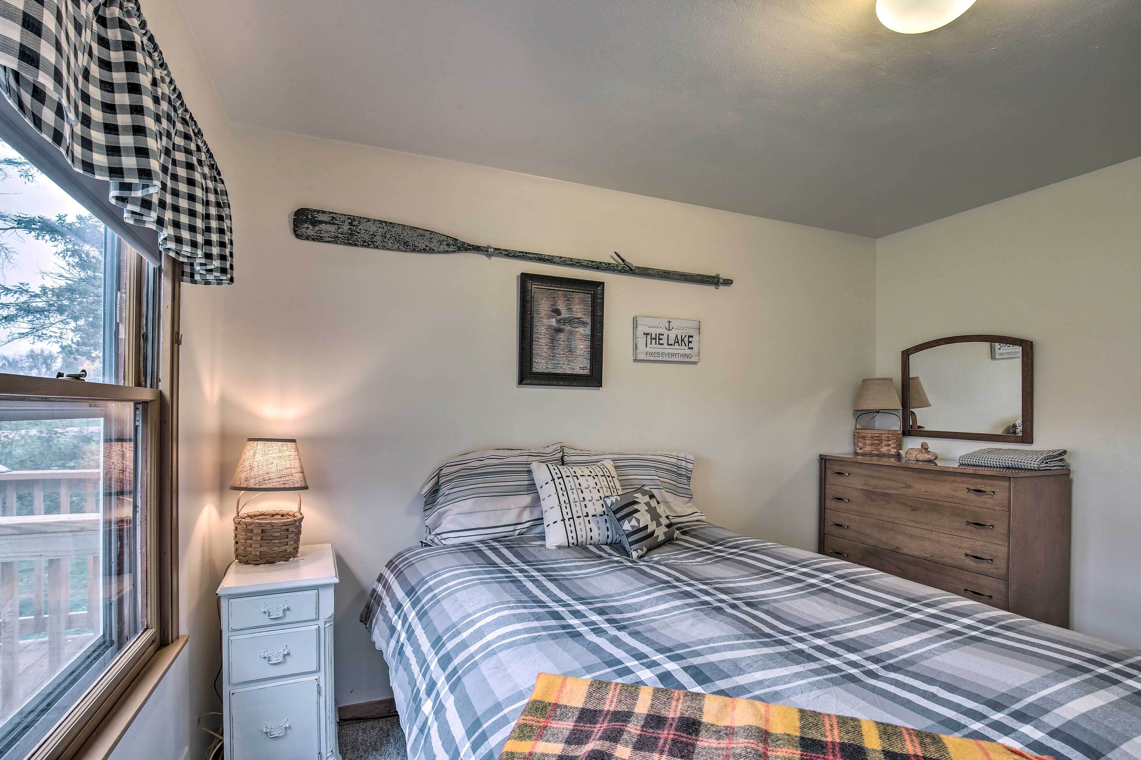 Une chambre à coucher comprenant un lit, une commode, une lampe, une fenêtre et des éléments de décoration murale.