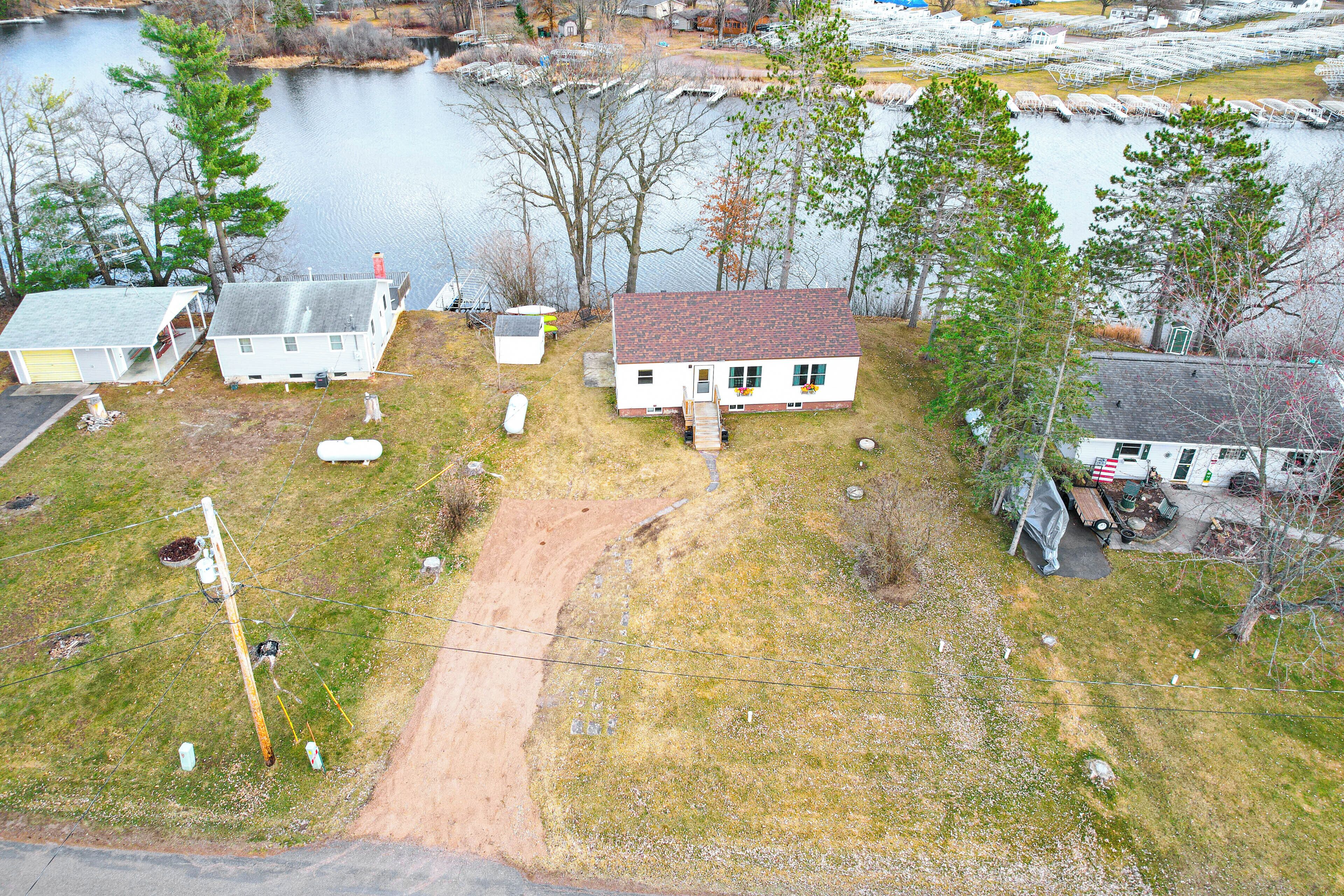 Un quartier résidentiel avec des maisons situées pr ès d’un lac, un chemin de terre et un poteau électrique.