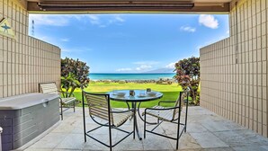 Un patio coperto con tavolo e sedie, una vasca idromassaggio e vista sulla spiaggia e sull'oceano.