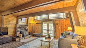 A cozy log cabin interior with a stone fireplace, a television, and a comfortable seating area with a couch and a coffee table. - Pet-friendly Cottage, Walk From Big Bear Village! (Big Bear Lake)