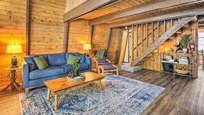 Ein gemütliches Zimmer mit einem blauen Sofa, einem Holztisch und einer Treppe.