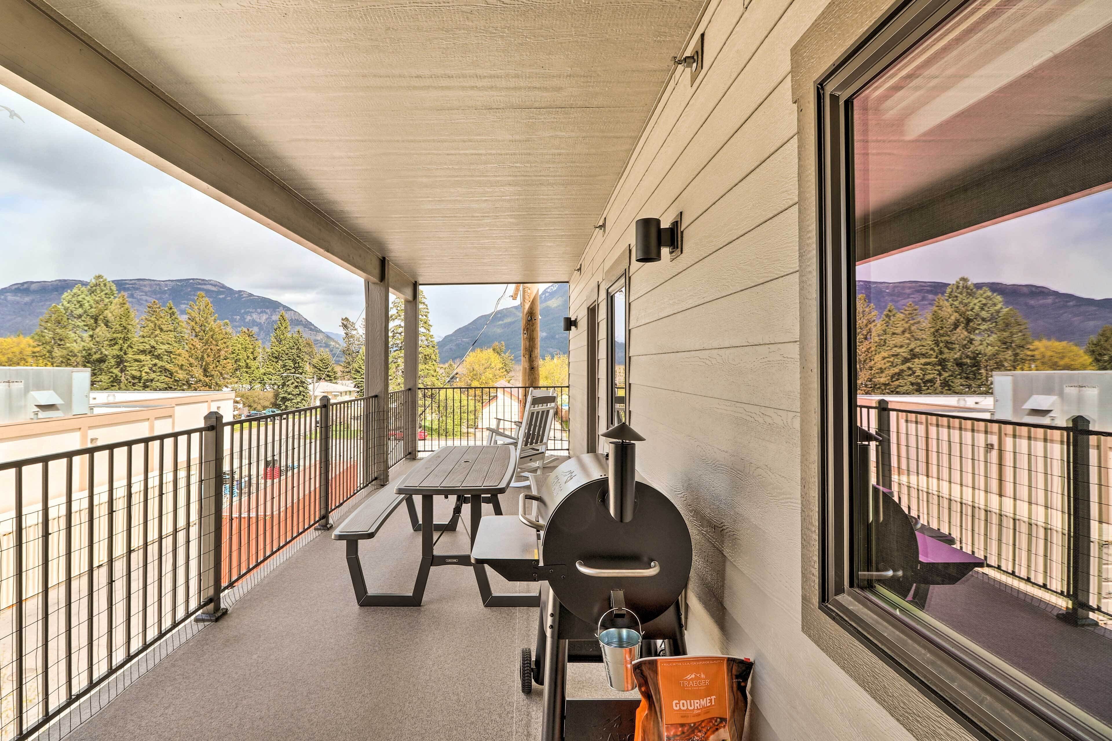 A covered patio with a grill, picnic table, and a scenic mountain view.