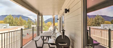 A covered patio with a grill, picnic table, and a scenic mountain view.