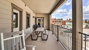 A balcony with a picnic table and chairs, a view of the street, and a building with a light-colored exterior. - Cozy Columbia Falls Condo w/ Private Balcony! (Columbia Falls)