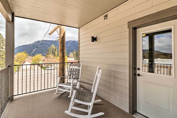 A balcony with two rocking chairs, a door, and a view of mountains. - Cozy Columbia Falls Condo w/ Private Balcony! (Columbia Falls)