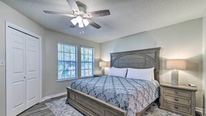 Une chambre à coucher avec un lit en bois, deux tables de chevet avec des lampes, un ventilateur de plafond et une fenêtre avec des stores.