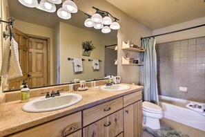 A bathroom with two sinks, a toilet, and a bathtub. There are overhead lights, a towel rack, and a mirror. - Hike + Fish: Pagosa Springs Townhome w/ View! (Pagosa Springs)