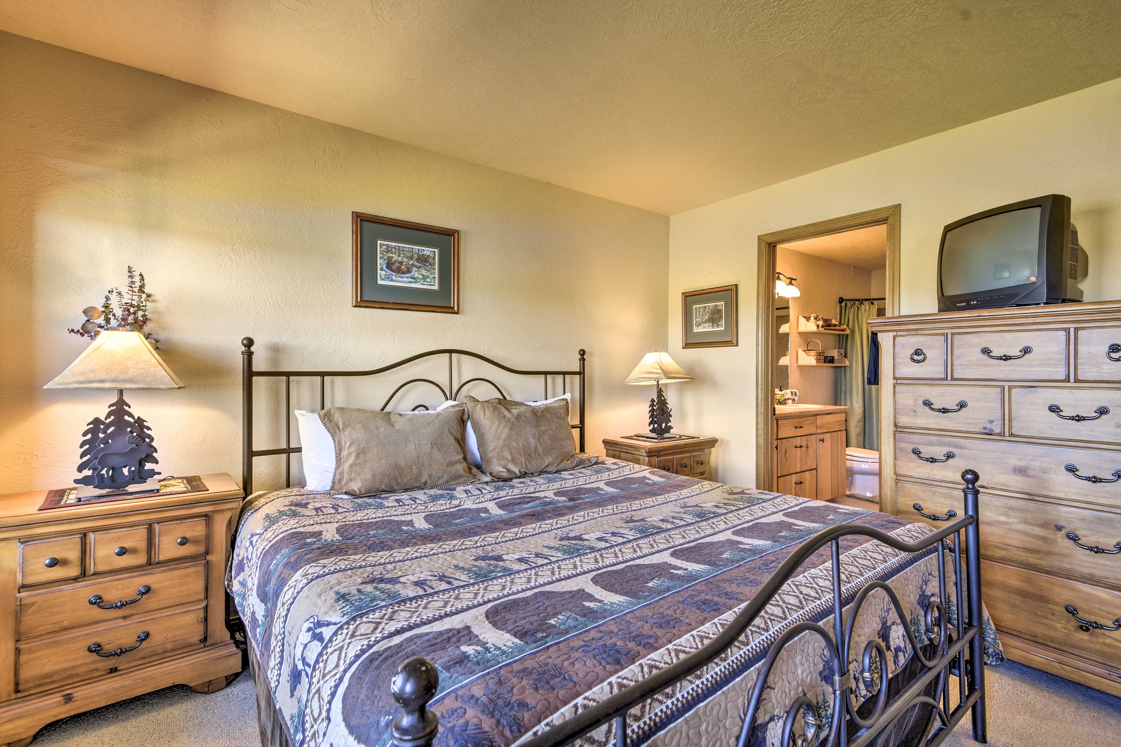 A bedroom with a bed, two bedside tables, a dresser, and a television.