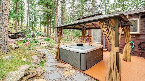 A hot tub in a forested area with a wooden deck and a pergola. - 330760: Home w/ Hot Tub - 11 Mi to Rainbow Falls (Woodland Park)