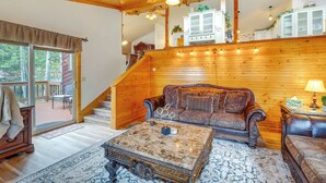 A cozy living room with a wooden ceiling, a fireplace, a sofa, a coffee table, and a staircase leading to an upper level. - 330760: Home w/ Hot Tub - 11 Mi to Rainbow Falls (Woodland Park)