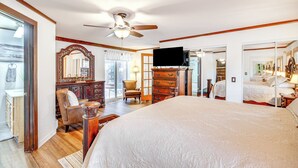A spacious bedroom with a large bed, a ceiling fan, a TV, and a mirror. - 330760: Home w/ Hot Tub - 11 Mi to Rainbow Falls (Woodland Park)