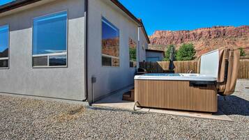 A modern building with large windows, a hot tub, and a view of red rock formations.