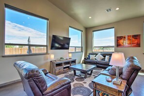A spacious living room with leather sofas, a coffee table, and a TV mounted on the wall. - Upscale Moab Townhome w/ Hot Tub: 20 Min to Arches (Moab)
