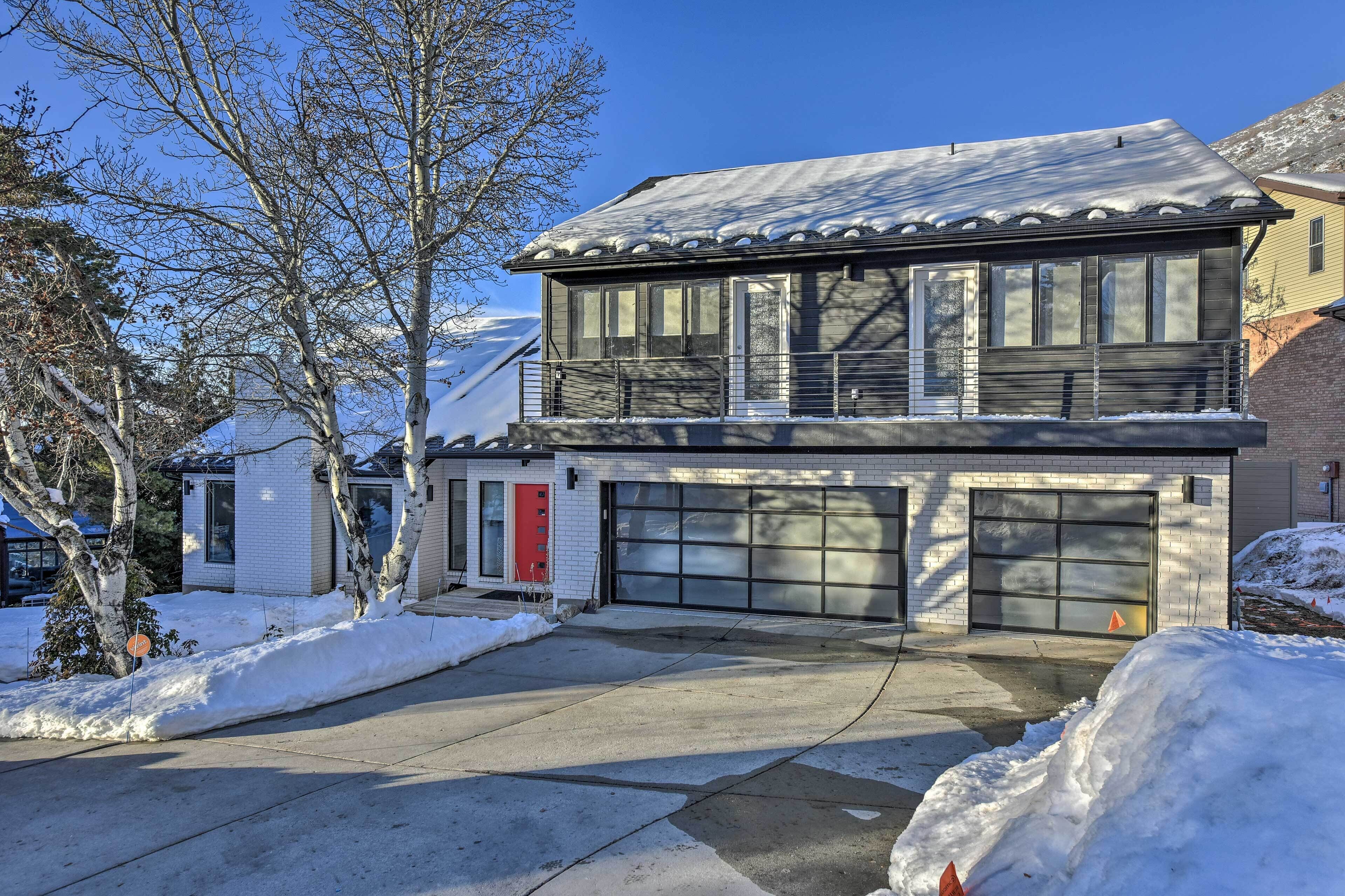 Une maison à deux étages avec un garage, une porte rouge et de la neige au sol.