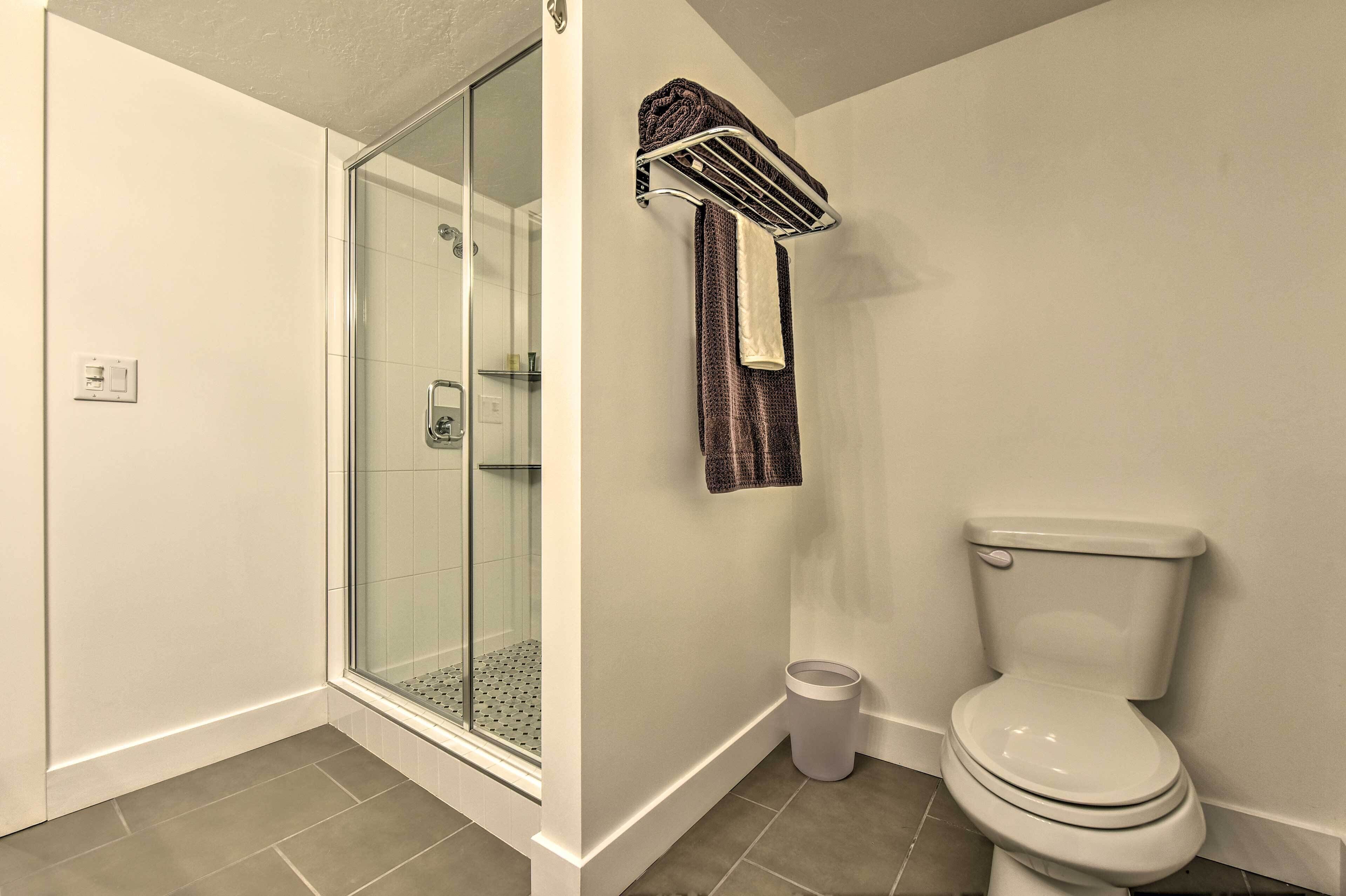 A bathroom with a glass shower enclosure, a toilet, and a towel rack.