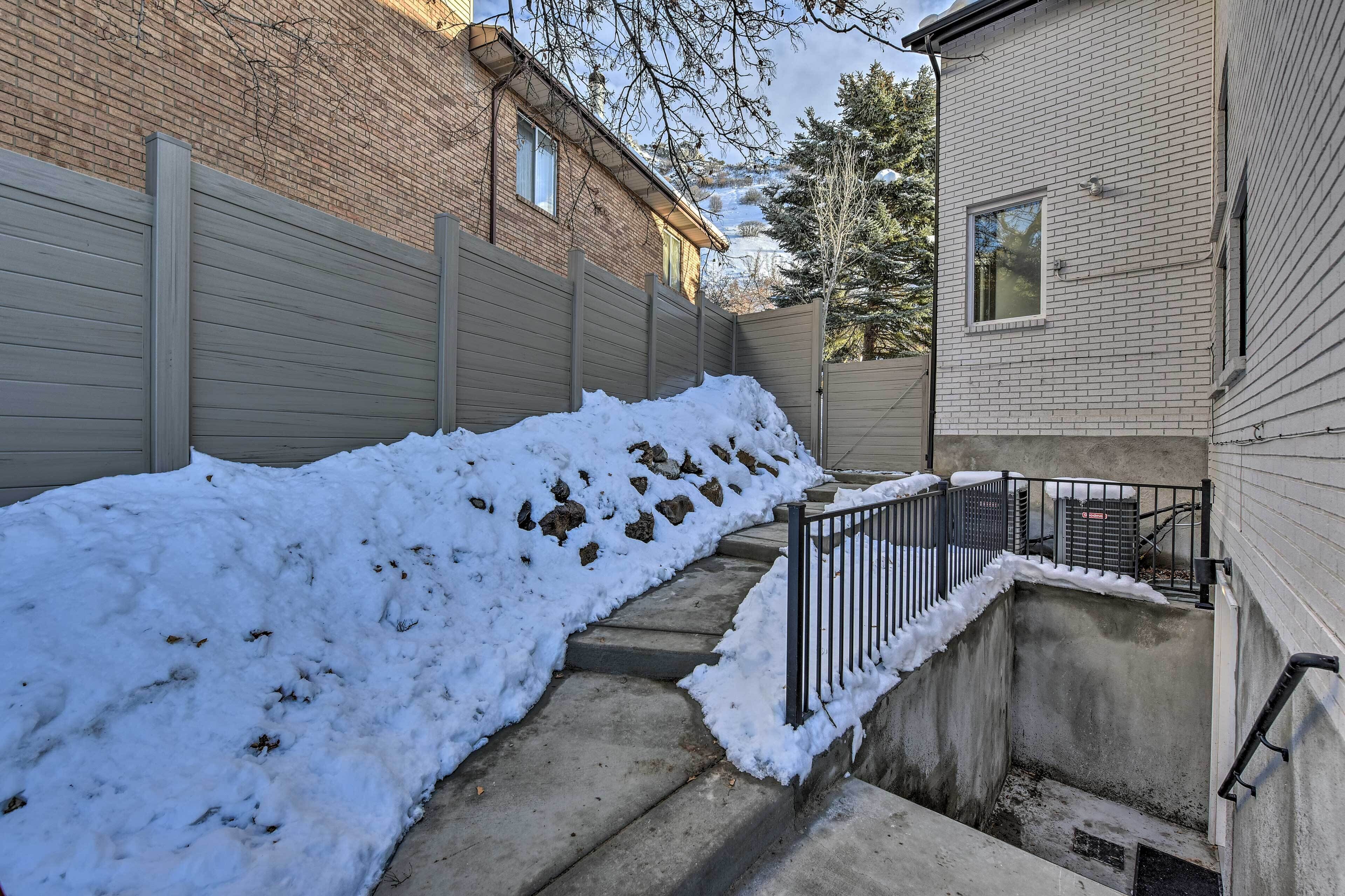 Un escalier extérieur recouvert de neige mène à un bâtiment dont la façade est en briques et l’extérieur est peint en blanc.