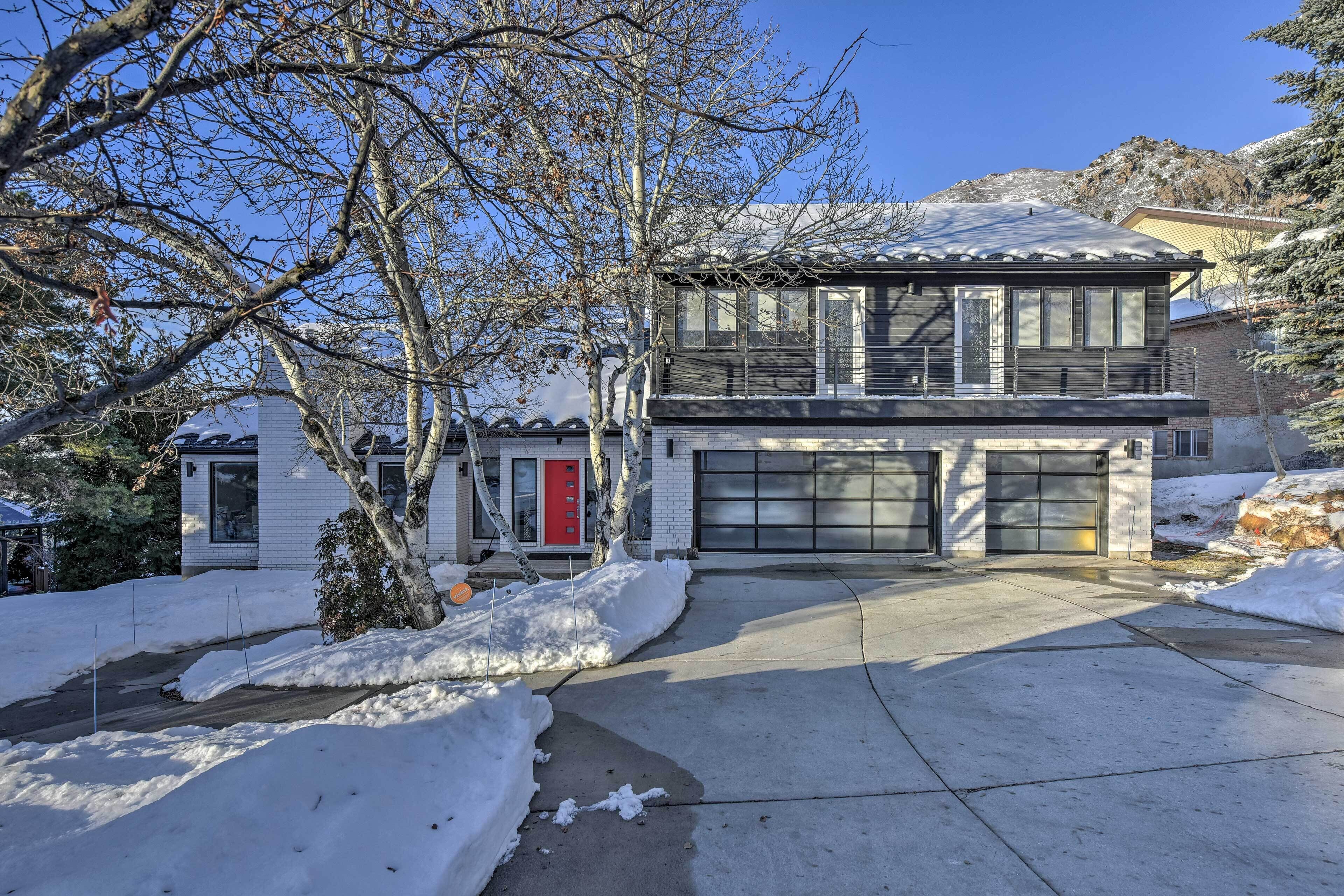 Ein zweistöckiges Haus mit Garage, umgeben von schneebedecktem Gelände und Bäumen.