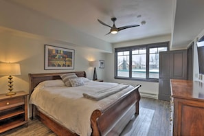 Un dormitorio con cama de madera, ventilador de techo, ventana con vistas y cómoda.