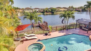 A swimming pool with a hot tub, lounge chairs, and a view of a lake and houses in the background. - Spacious Miami Retreat w/ Grill, Pool & Dock! (Miami)