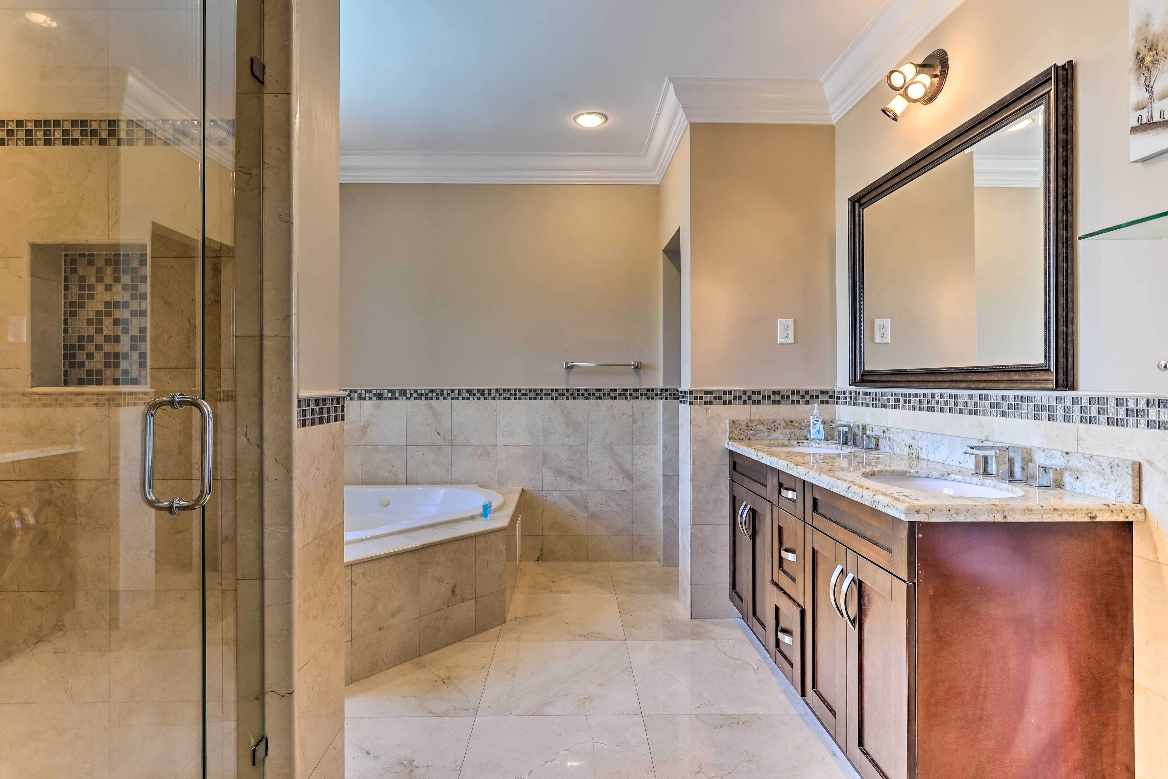 A modern bathroom with a glass shower enclosure, a freestanding bathtub, and a vanity with dual sinks.