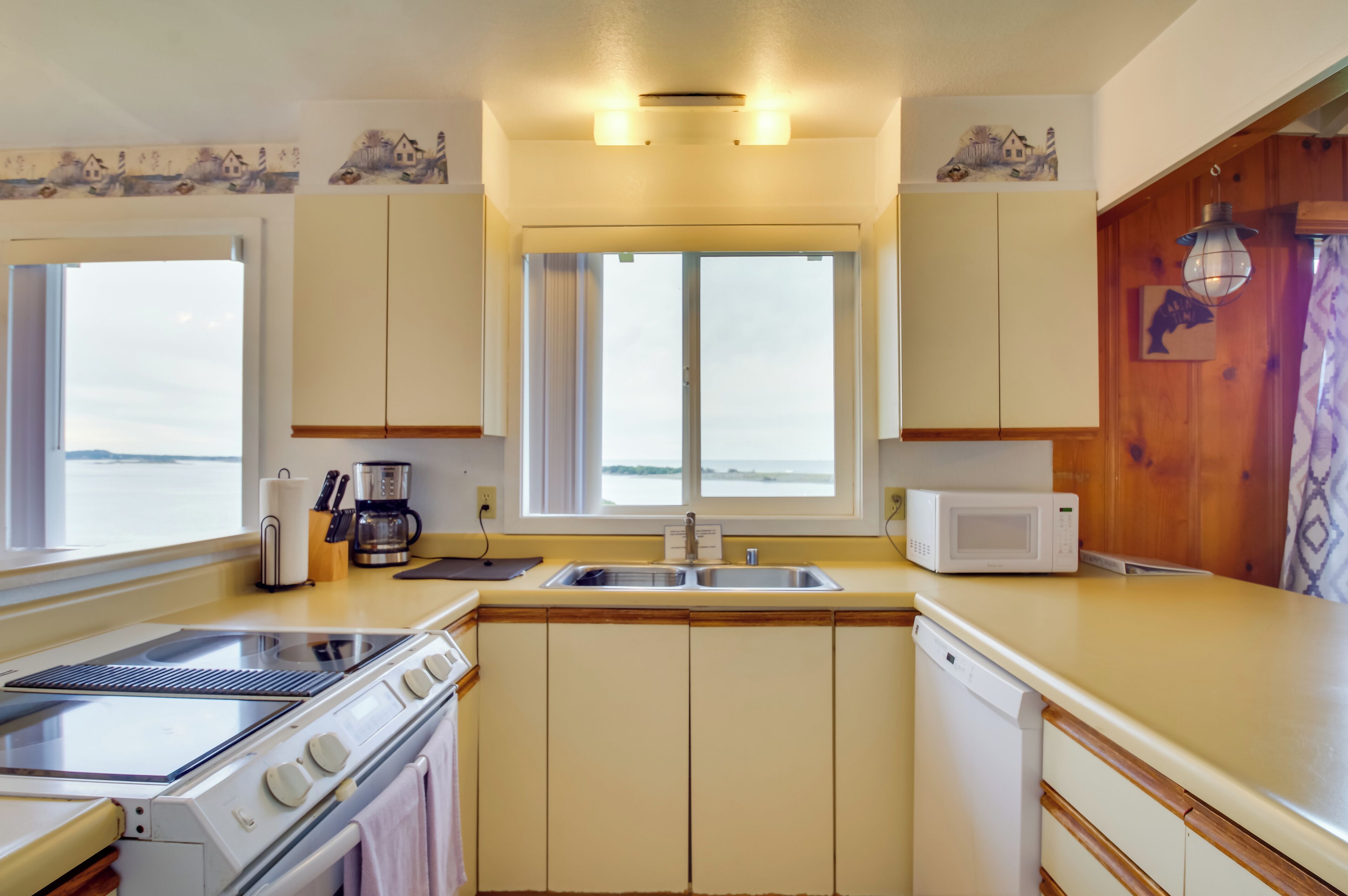 A kitchen with a stove, microwave, sink, and wooden cabinets.