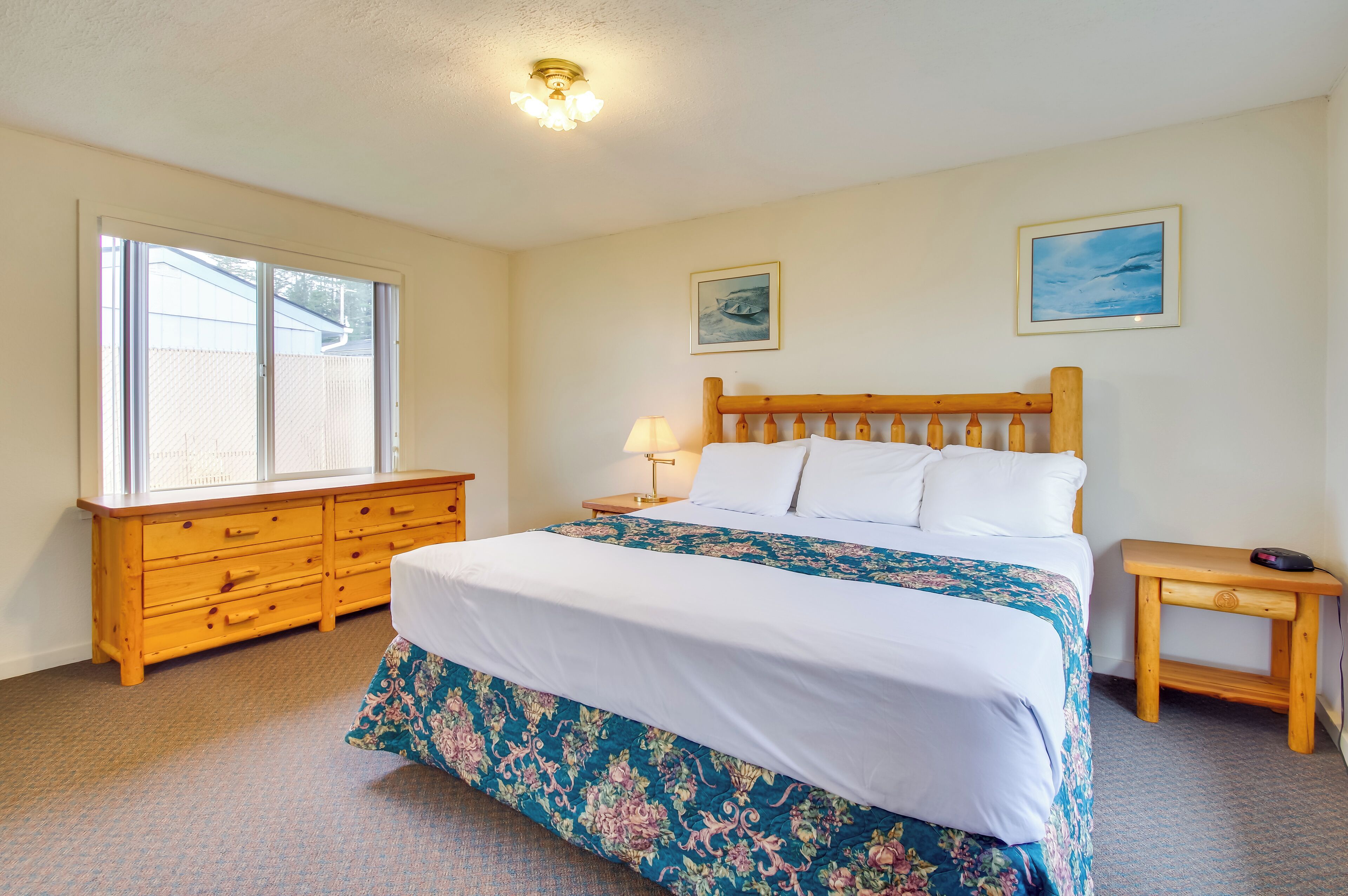 A bedroom with a bed, wooden dresser, and a nightstand.