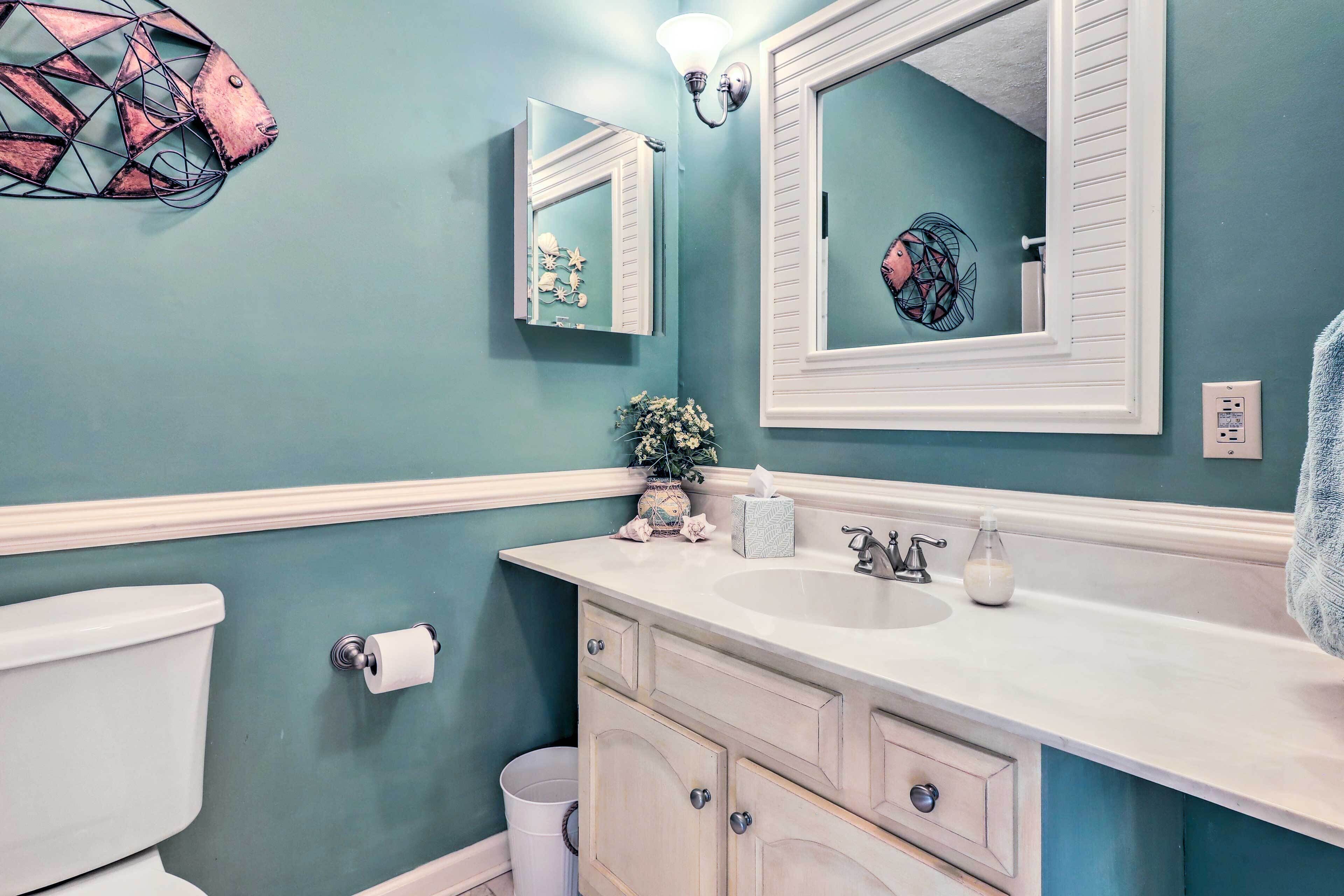 A bathroom with teal walls, a white sink, and a mirror above it.