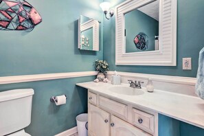 Ein Badezimmer mit türkis-blauen Wänden, einem weißen Waschbecken und einem Spiegel darüber.