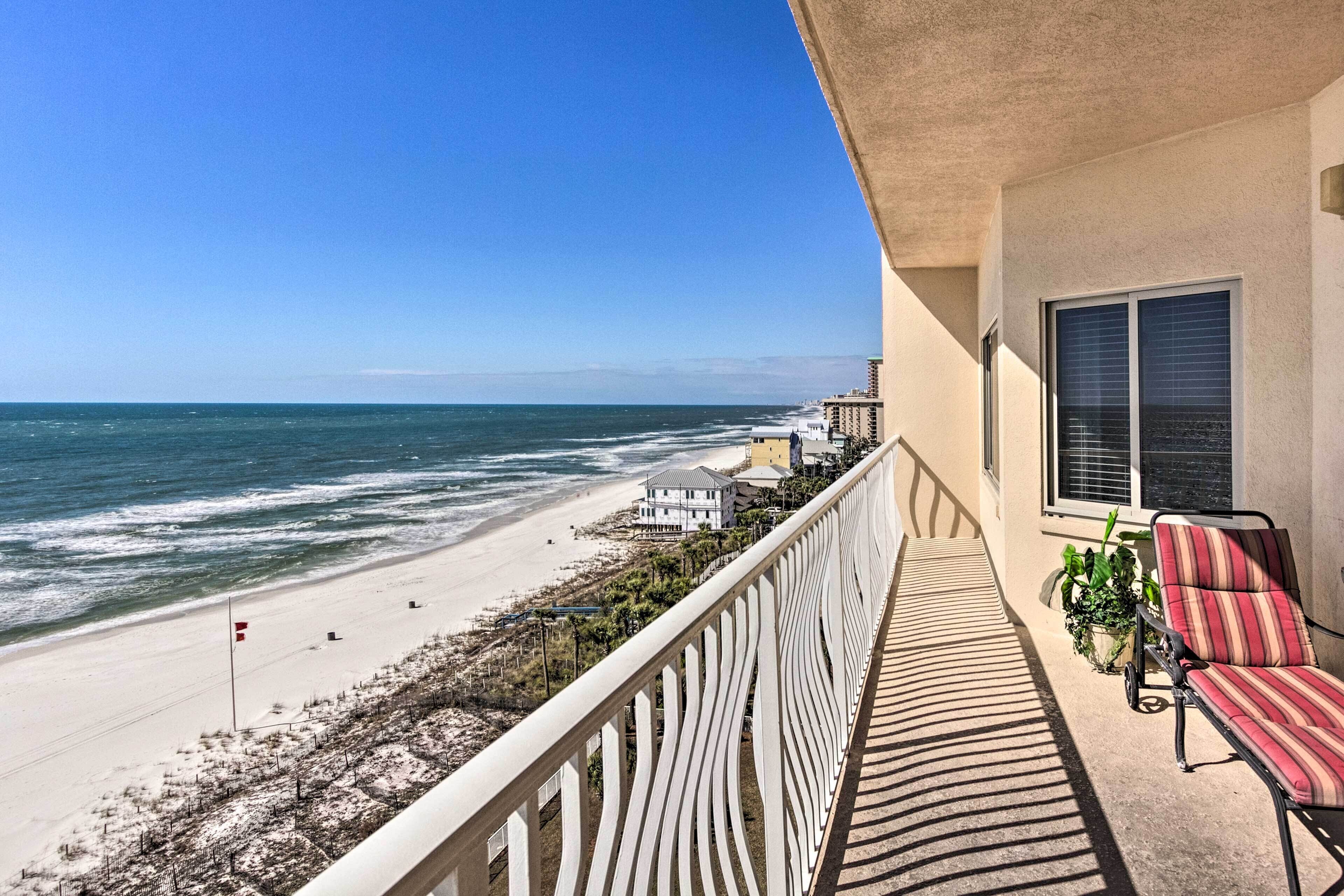 A balcony with a view of the beach, a chair, and a potted plant.