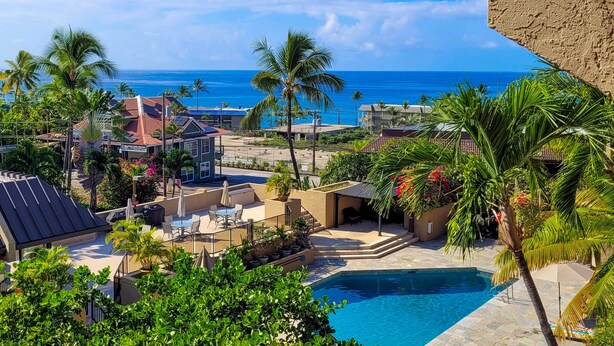 A resort with a swimming pool, palm trees, and a view of the ocean.