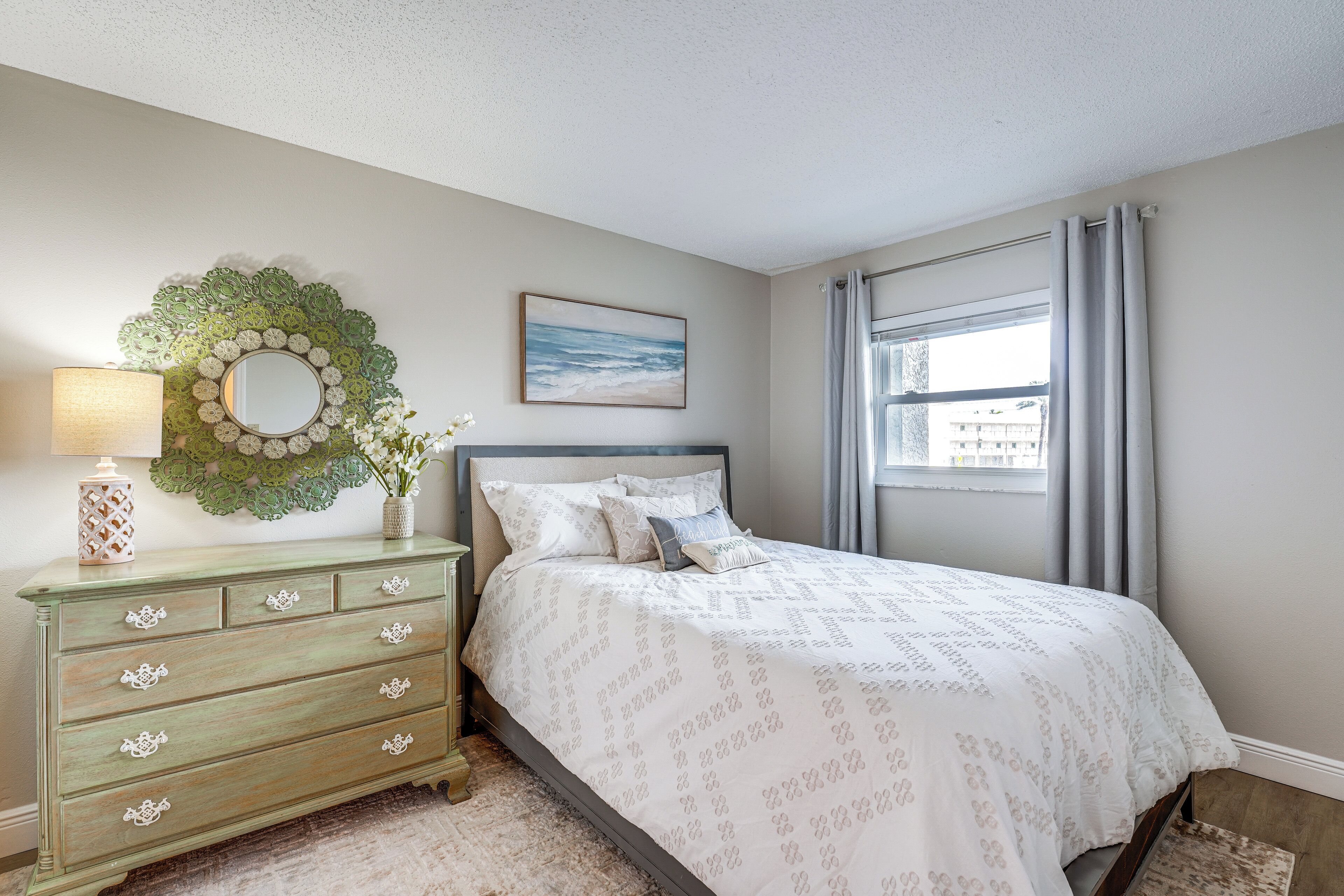 A bedroom with a bed, dresser, and a decorative mirror.