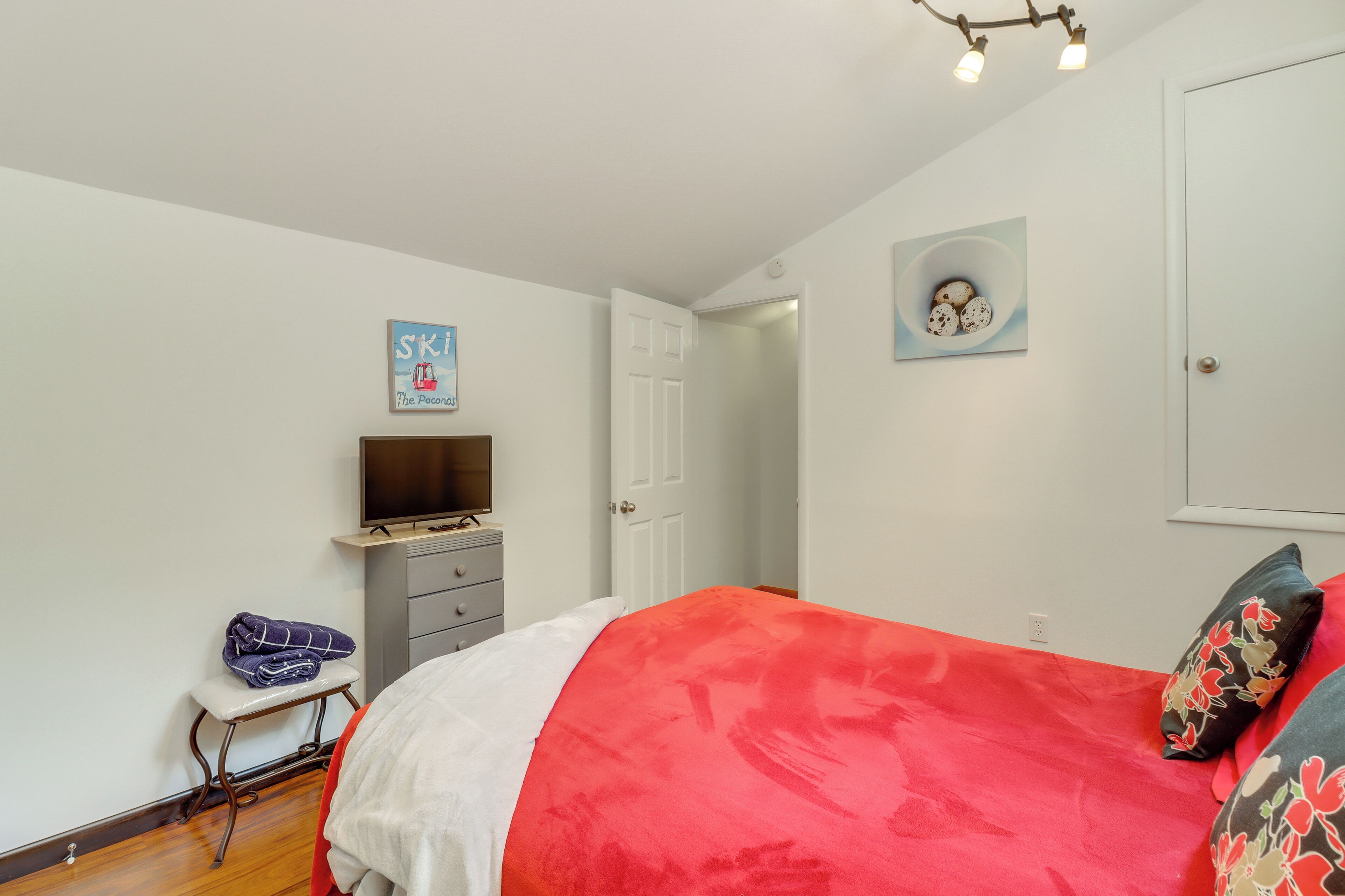 A bedroom with a bed, a television on a dresser, a door, and a wall with a sign.