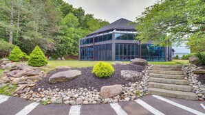 A modern building with a glass facade, surrounded by a landscaped area with rocks and a small tree. - Indoor Pool Near Skiing Tannersville Townhome (Tannersville)