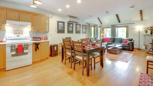 A spacious kitchen with wooden cabinets, a white stove, and a dining area with a table and chairs. - Indoor Pool Near Skiing Tannersville Townhome (Tannersville)