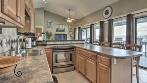 A modern kitchen with granite countertops, stainless steel appliances, wooden cabinets, and a large island.