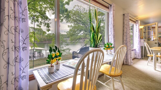 Una habitación con un ventanal grande, una mesa de comedor con sillas y una planta en maceta en el alféizar.