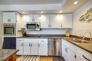 Una cocina moderna con gabinetes blancos, electrodomésticos de acero inoxidable y encimera de granito.