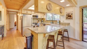 A spacious kitchen with wooden cabinets, a granite countertop, and a large island with bar stools.
