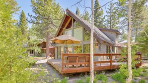 A cabin with a wooden deck, large windows, and outdoor seating.